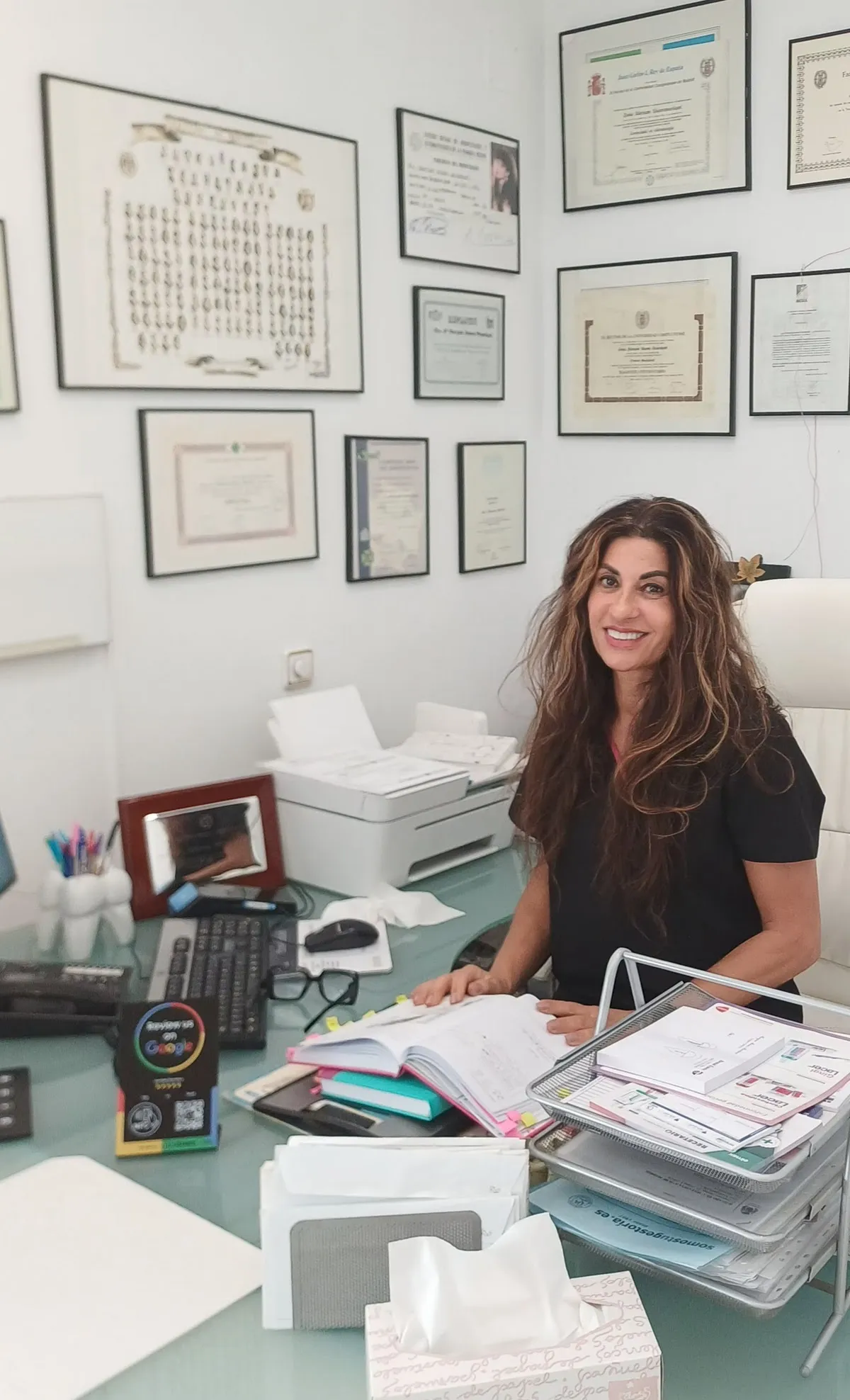 Dra. Maryam en su consulta con titulaciones al fondo — Dental Estetic Oeste Getafe